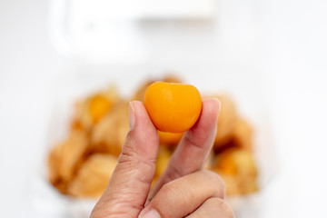 hand fingers holding cape gooseberry (physalis) isolated on white background