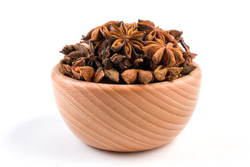 anise stars in wooden bowl isolated on white background.