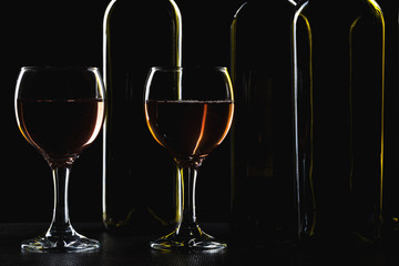 Bottles of wine and different glasses of wine on a dark background