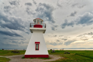 Fototapeta na wymiar The lighthouse at Carleton, Gaspesie, Quebec with a dramatic stormy sky behind