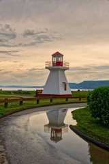 Fototapeta na wymiar The lighthouse at Carleton, Gaspesie, Quebec reflected in a puddle after a summer storm