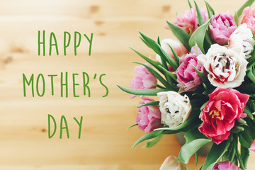 Happy Mother's Day text sign on beautiful double peony tulips bouquet in vase on wooden table. Stylish floral greeting card. Thank you,mom