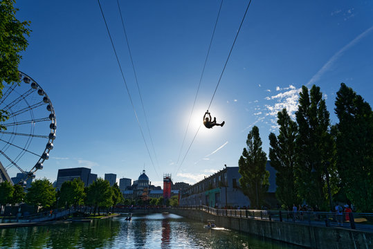 A person descending the zipline in Montreal Old Port with La Grande Roue de Montreal behind