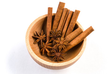 anise stars and cinnamon sticks in wooden bowl isolated on white background