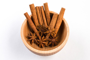 anise stars and cinnamon sticks in wooden bowl isolated on white background