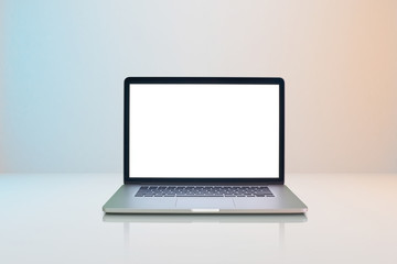 Laptop with white blank screen on milky white background with slightly blue and orange lighting .