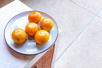 Close up oranges in white ceramic plate with blurred background and empty copy space