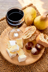 Rustic cheese plate in the interior. brie, pears, walnut, bread, red wine