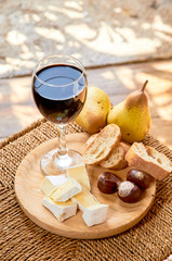 Rustic cheese plate in the interior. brie, pears, walnut, bread, red wine