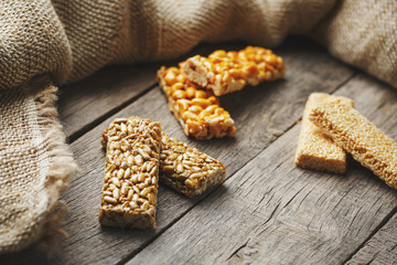 Assorted kozinaki, on old vintage background, with burlap fabric. Country style. Delicious sweets from the seeds of sunflower, sesame and peanuts, covered with shiny glaze.