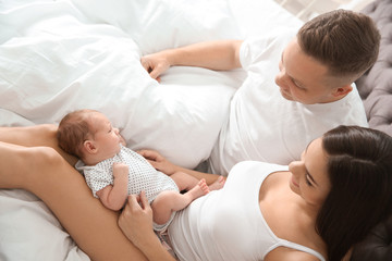 Obraz na płótnie Canvas Happy couple with their newborn baby on bed