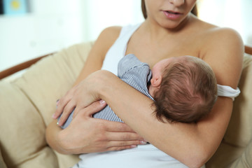 Obraz na płótnie Canvas Young woman breastfeeding her baby at home, closeup