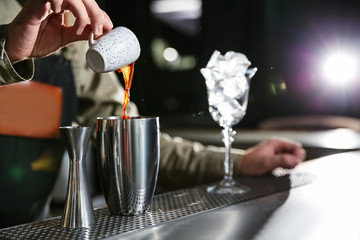 Barman pouring espresso into shaker at counter, closeup with space for text. Making martini cocktail
