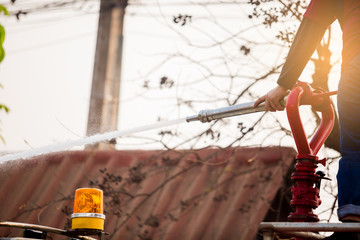 staff standing on water truck with holding fire fighting nozzle and hose with spray water
