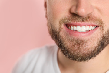 Fototapeta premium Young man with healthy teeth on color background, closeup. Space for text