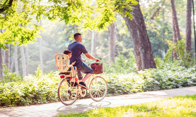 Fototapeta premium family in park. father with kid on bicycles having fun in park. .