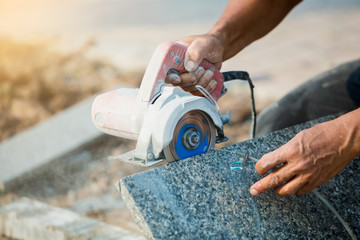 worker cutting granite stone with an diamond electric saw blade and use water to prevent dust and heat - obrazy, fototapety, plakaty