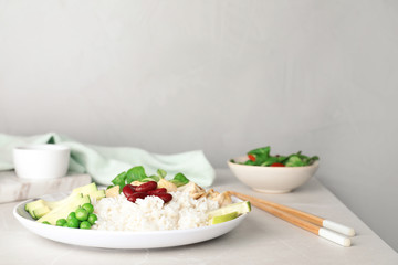 Plate of boiled rice with vegetables and meat on table. Space for text