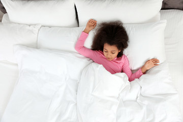 Cute little African-American girl sleeping in bed, top view