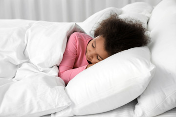 Cute little African-American girl sleeping in bed