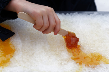 Close up of a young (5 yr old) child's hand rolling maple syrup taffy onto a stick