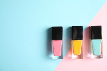 Bottles of nail polish on color background, top view with space for text - obrazy, fototapety, plakaty