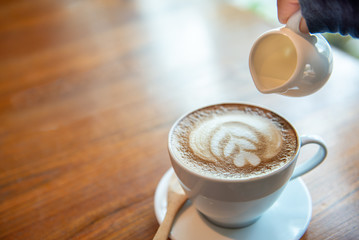 Coffee Espresso. Cup Of Coffee with latte art foam on wood table near window with light shade.