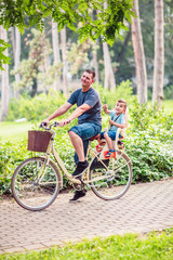 Dad and son riding bicycles outdoors.