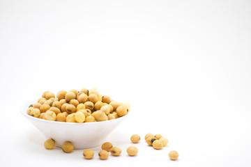 Soy seeds in white bowl and some drop out on white background