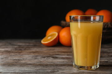 Glass of orange juice on wooden table. Space for text