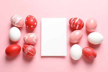 Flat lay composition of painted Easter eggs and card on color background, space for text