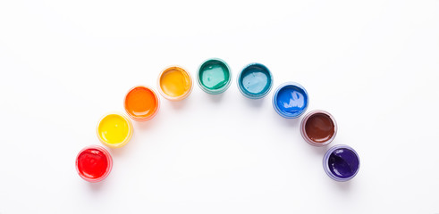 Multicolored gouache on a white background Rainbow shape Isolated Paints in containers Top view Banner Horizontal