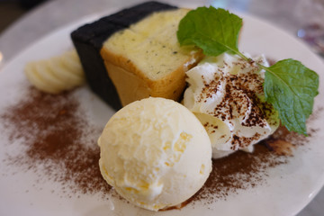 Vanilla icecream and two tones toast serve with fresh whipping cream and slice banana decorating by coco powder and mint leaf