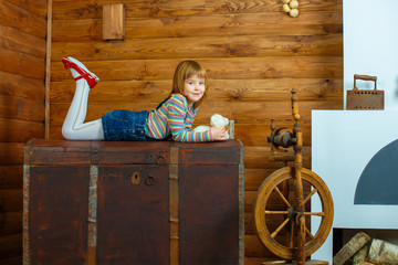 Girl Masha is lying on the old chest and smiling.