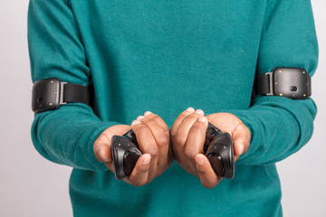 Hands of dark- skinned man holding gamepads from virtual reality headset. Grey background. VR...