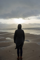 Woman on Cold Beach Looking Towards Sea