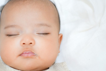 Newborn baby sleeping and blew bubble out of her mouth - close up on white towel background