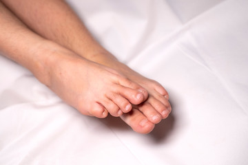 Fototapeta na wymiar Woman foot flexion on bed sheets color white