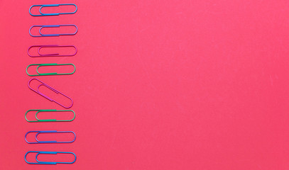 Colorful big paper clips on red color background