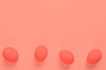 Four Easter eggs lying on bottom of trendy coral background. 