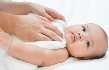 Mother hands wiping baby body after shower on white background