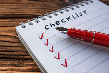 checklist, fountain pen on wooden table background. business planning.