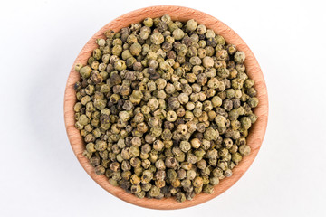 green pepper peppercorns  in wooden bowl isolated on white background. top view