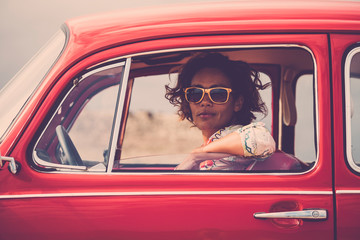 Serious lady on a old retro nice red car looking at you with open window glass - traveler with...