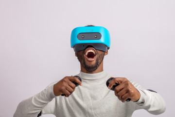 African happy overjoyed guy in VR glasses driving virtual car isolated over white background learning to drive a car. Virtual driving school or studio concept