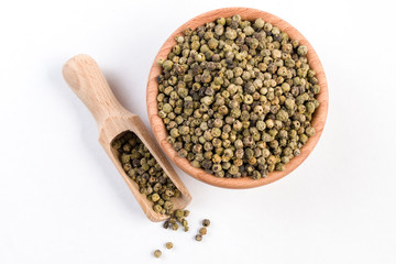 green pepper peppercorns  in wooden bowl and scoop isolated on white background