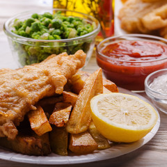 Traditional British street food fish and chips with ketchup sauce and mushy peas on paper plate