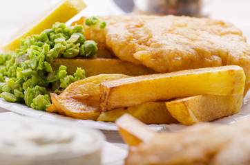 Traditional British street food fish and chips with mushy peas on parchment paper