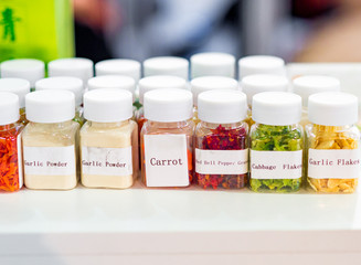 Dried vegetables in glass jars, onions, beets, carrots, pumpkin, bay leaf, banks on wooden background. Superfoods, herbs.