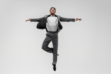 Happy businessman dancing in motion isolated on white studio background. Flexibility and grace in...